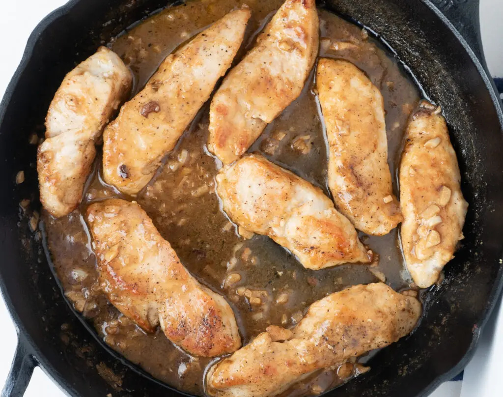 Chicken strips in a skillet with garlic lemon sauce