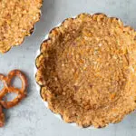 Mini baked pretzel pecan pie crust with pretzel and pecan garnish on the side.