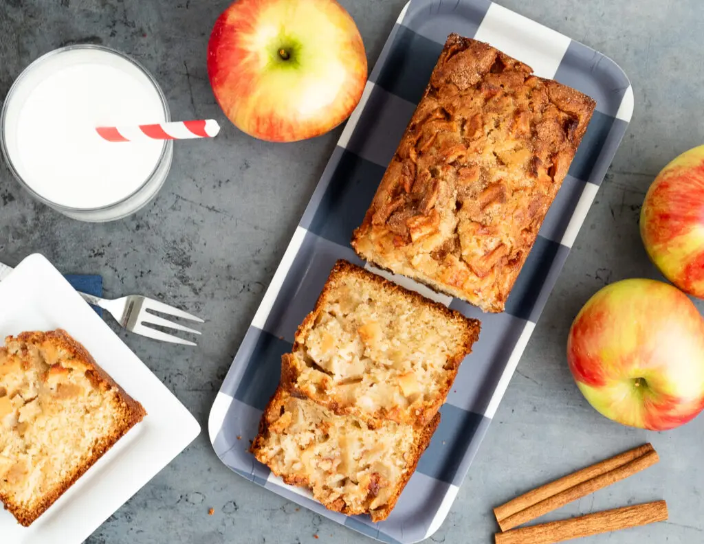 Jewish Apple Cake Quick bread Recipe apples and glass of milk with red and white striped straw and cinnamon sticks