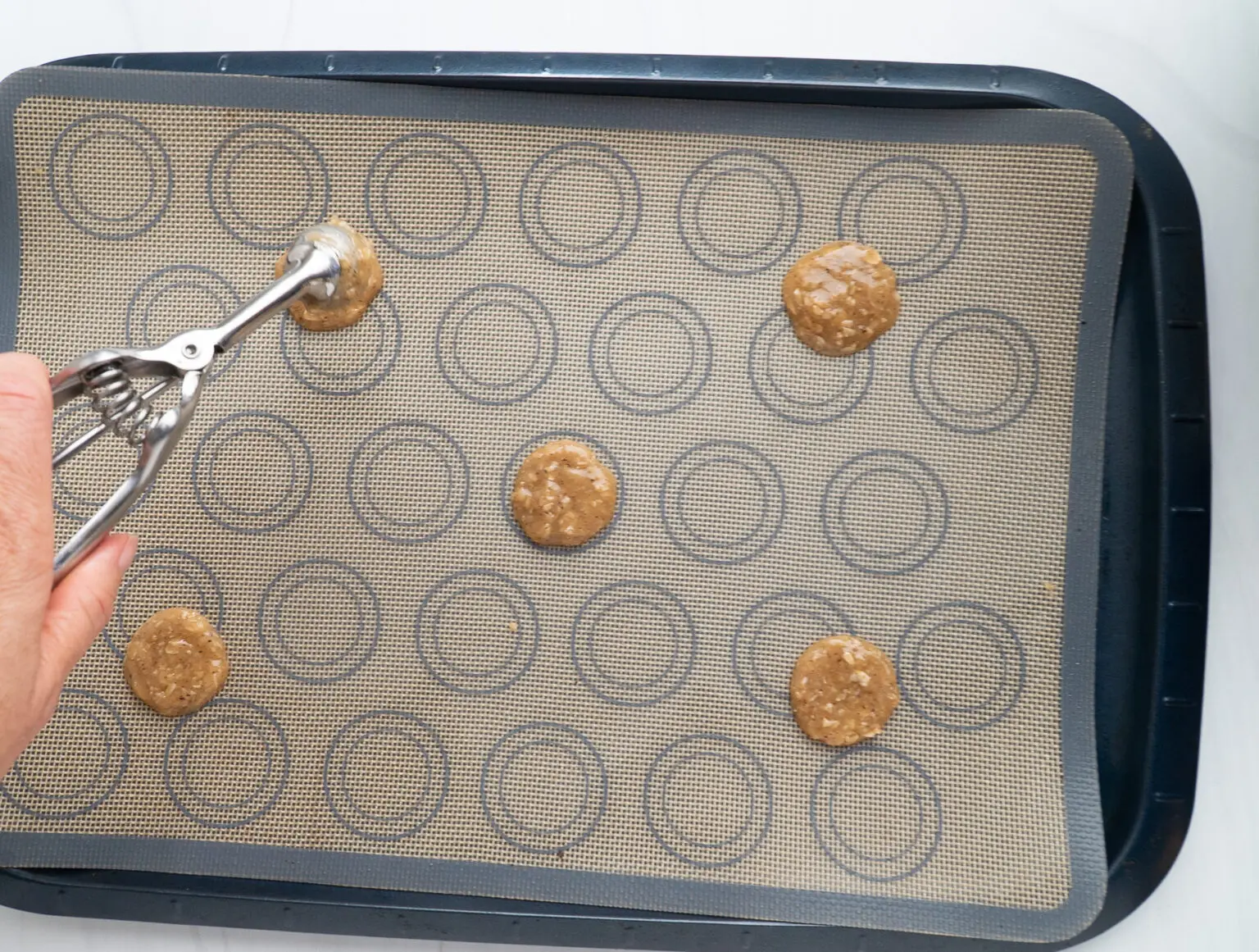 Scooping Brown Butter Irish Lace Cookies on a sheet pan