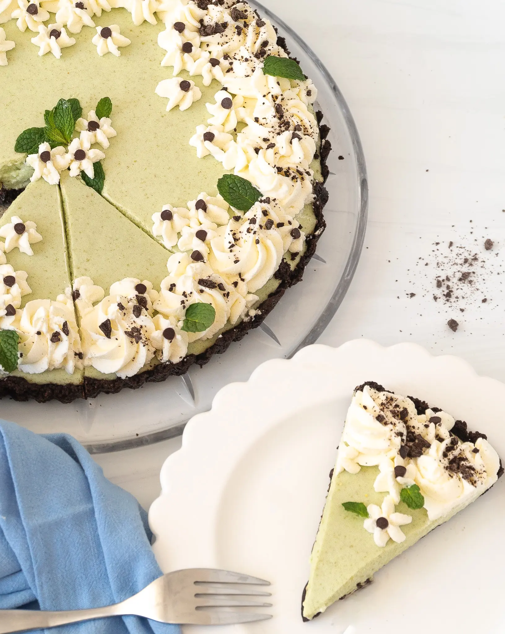 Lillian's Grasshopper Pie recipe cut slice on a plate and full pie in the background with a blue napkin.