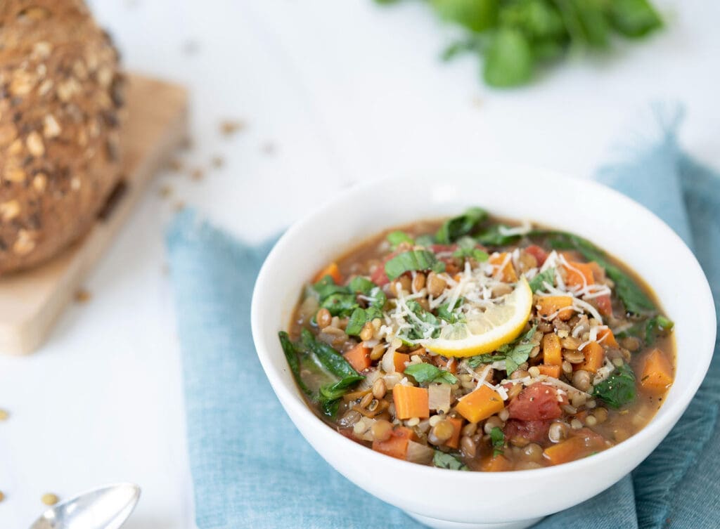 Lentil soup with carrots and peas and a lemon slice
