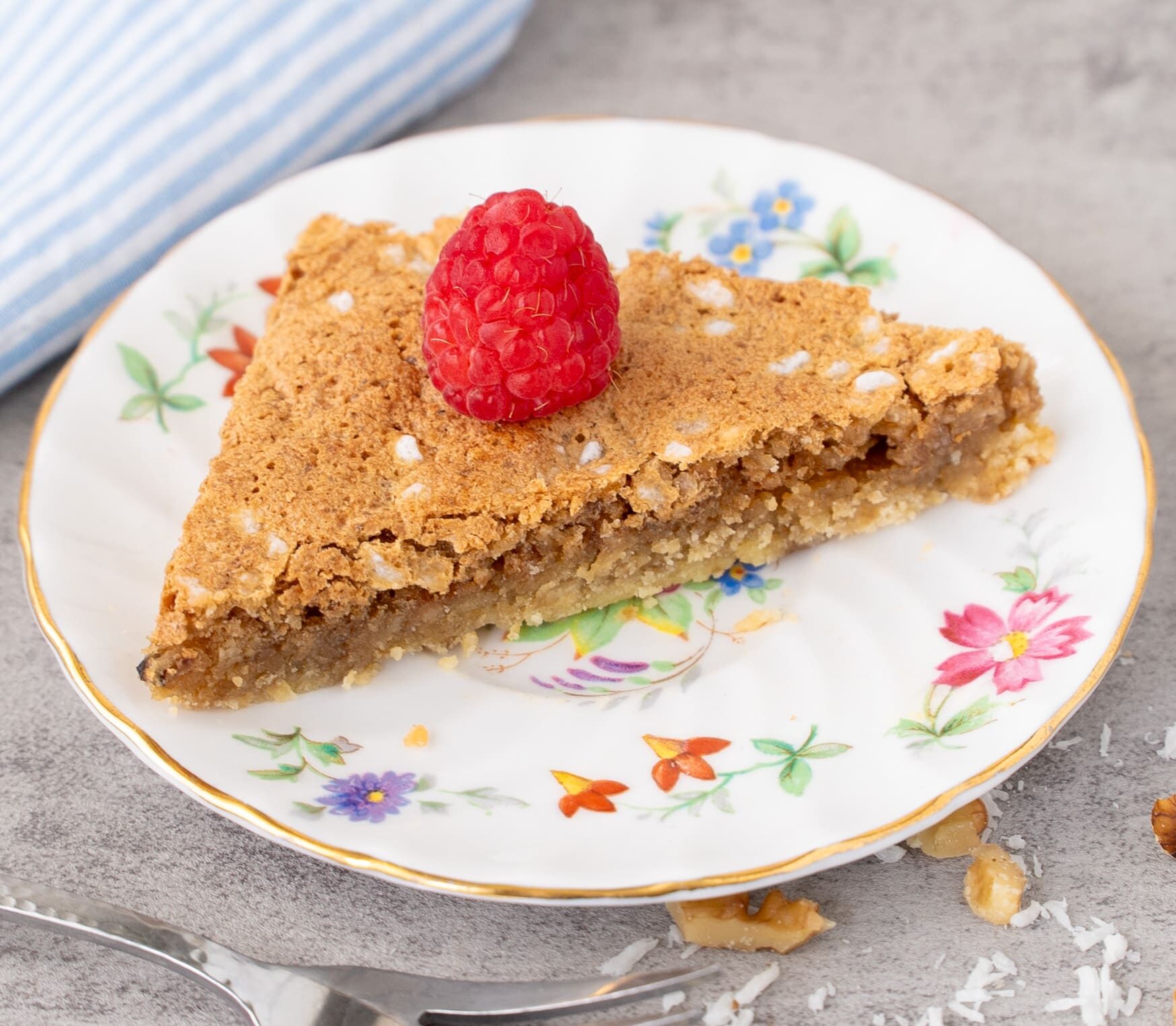 Butternut Bars on a small flowered dish with a raspberry