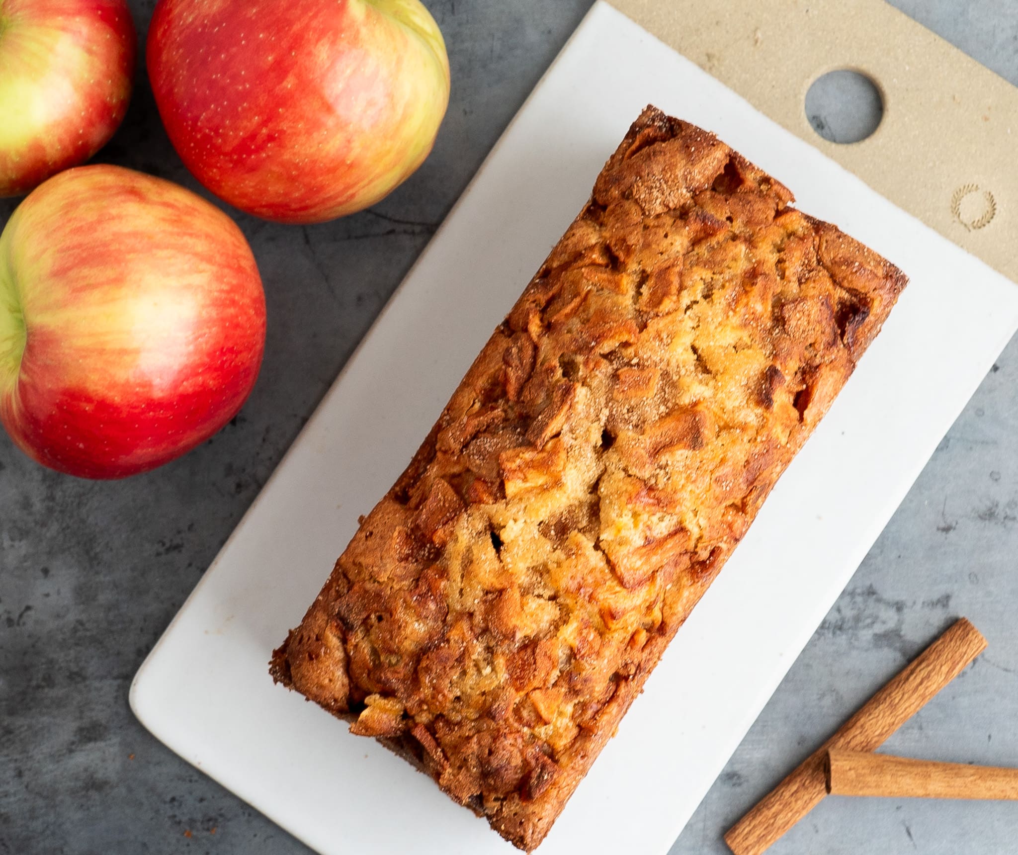 Jewish Apple Cake Quickbread whole Jewish Apple Cake Quick Break Recipe | Whole loaf on ceramic rectangular plate with apples in the corner
