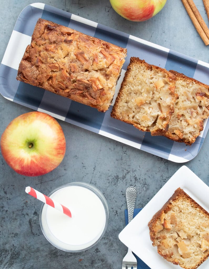 Hero shot overlay of Jewish Apple Cake on a blue and white checked plate with apples and cinnamon sticks in the background