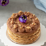 Heirloom walnut torte with espresso and mocha buttercream, topped with a fresh purple and yellow pansy.