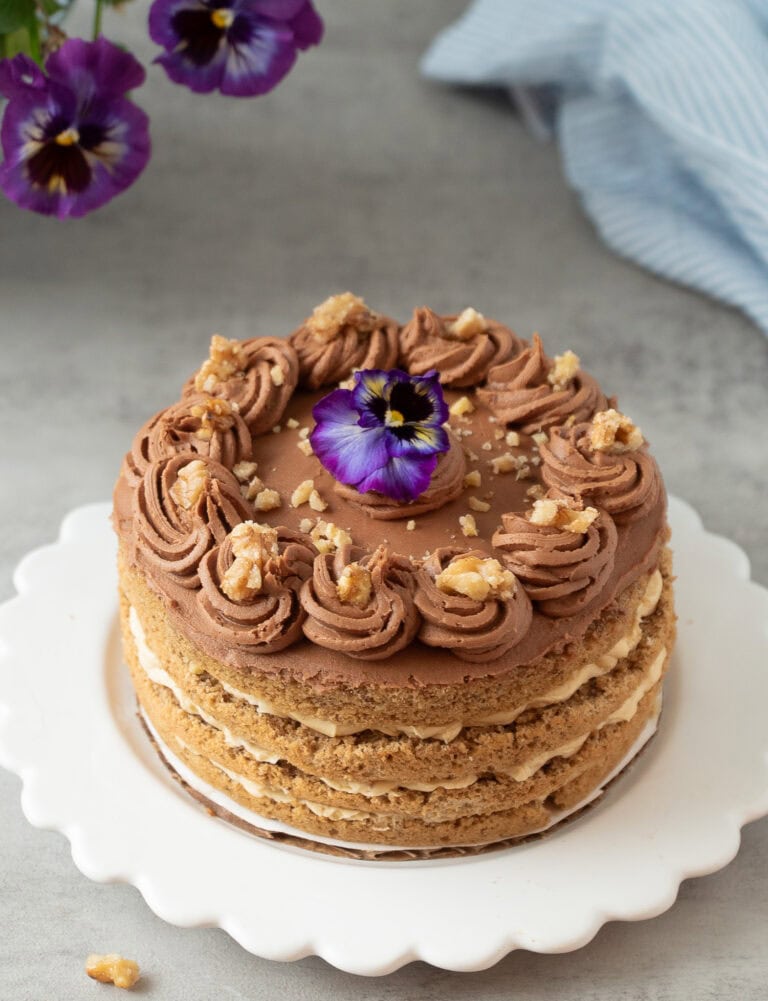 Heirloom walnut torte with espresso and mocha buttercream, topped with a fresh purple and yellow pansy.