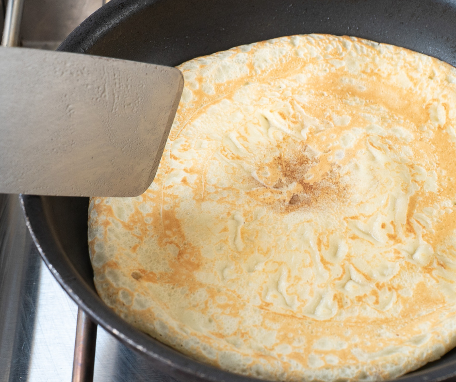 Austrian Pancake Soup - flipping over a golden pancake in a pan.