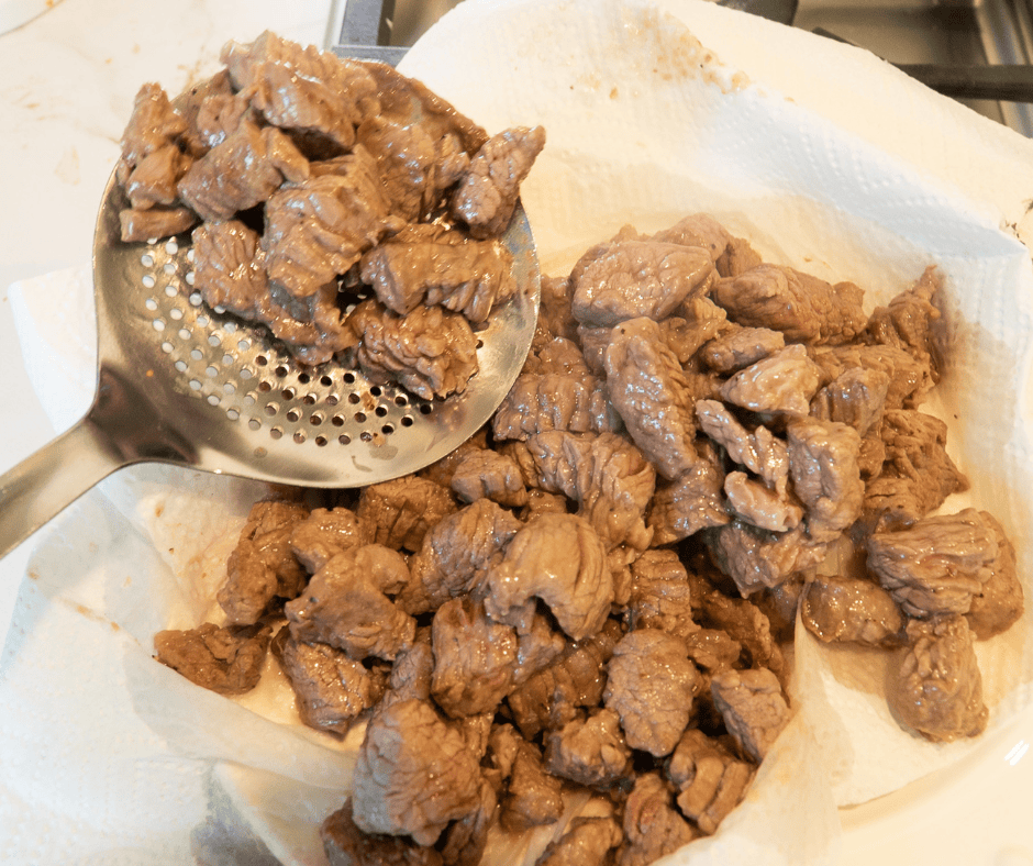 Removing cooked beef for beef stew with herb dumplings recipe and putting them on a plate. 