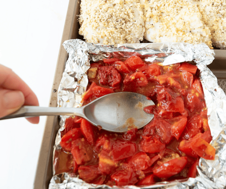 Spoon crushing cooked tomatoes to turn them into a rustic tomato sauce,