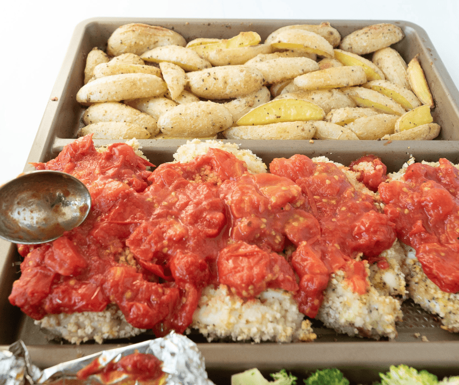 Putting tomato sauce on chicken cutlets for easy sheet pan chicken parmesan
