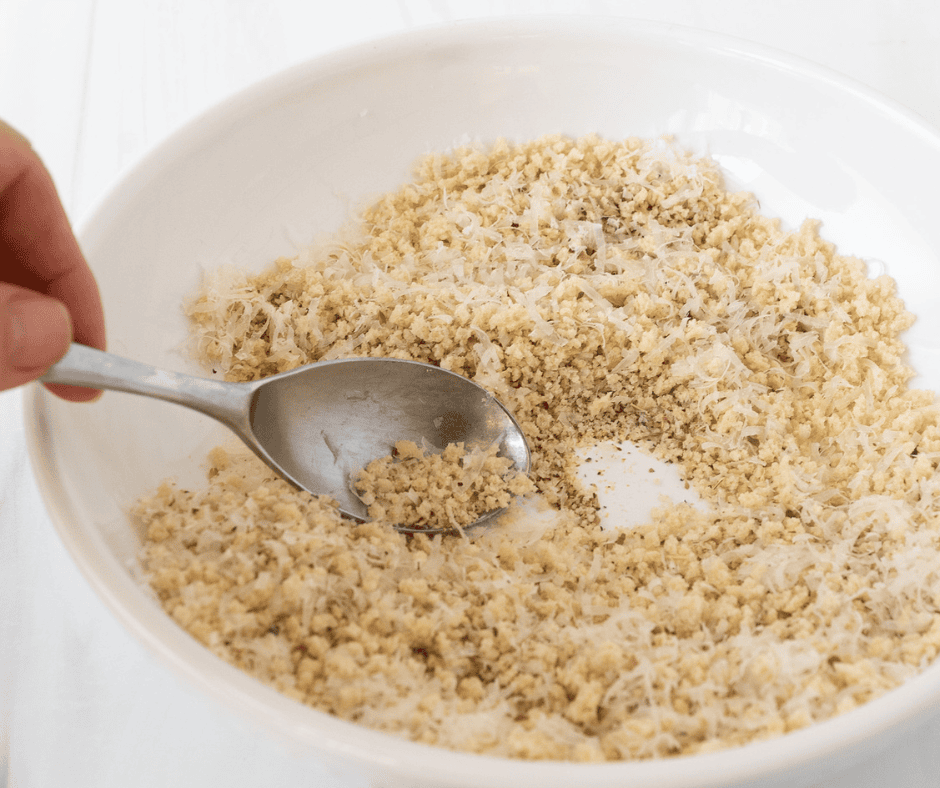 Photo of a hand holding a spoon to mix the bread crumb ingredients 