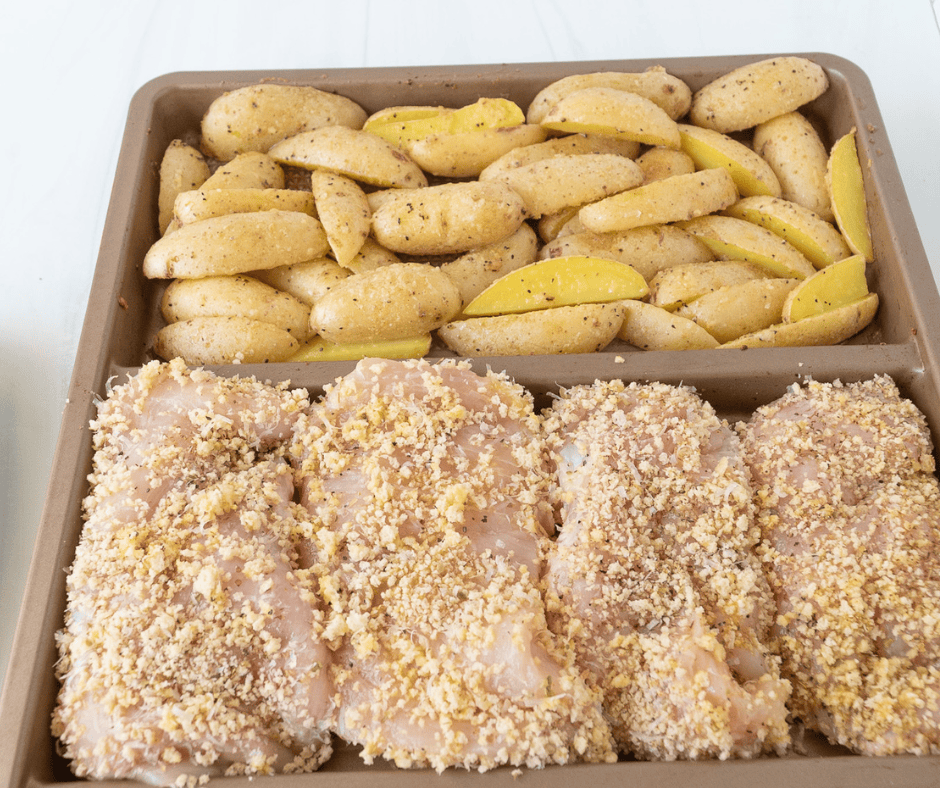 chicken and potatoes on a divided sheet pan ready to bake 