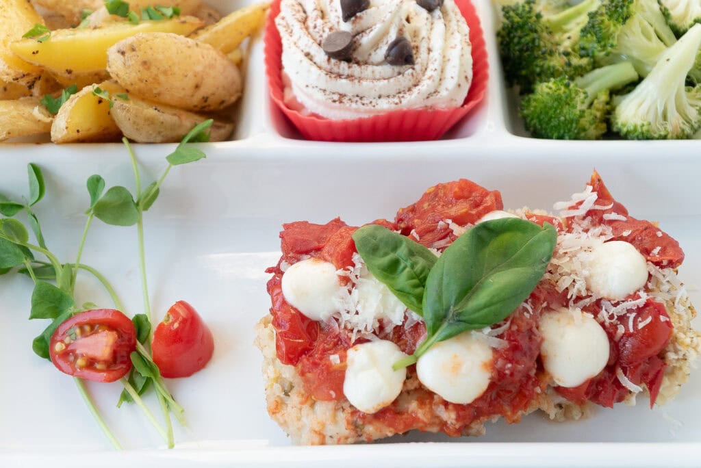 close-up of a chicken parmesan cutlet with side dishes in the background