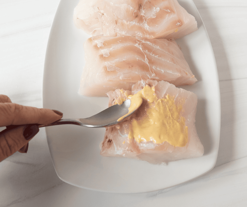Process picture of spreading mustard on a cod filet.