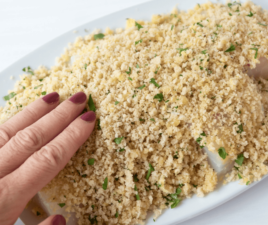 process picture of hand tapping panko crumb coating on fish.