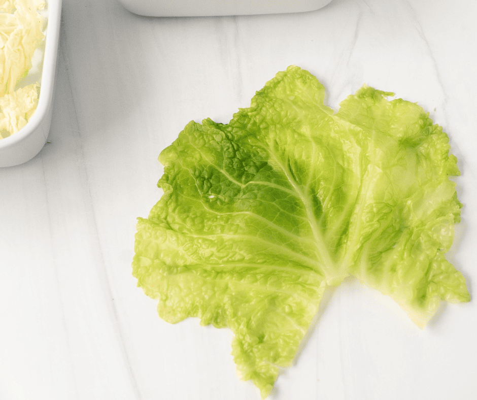 Steamed green cabbage leaf spread out on a surface.