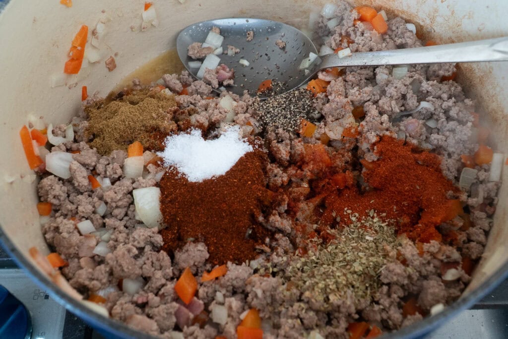 Adding spices to a pot for smoky turkey chili
