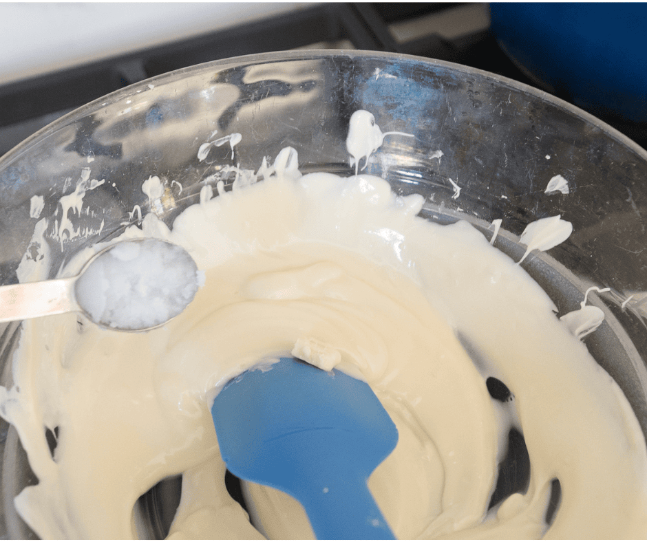 Melted white chocolate over a double boiler with a spoon of coconut oil.