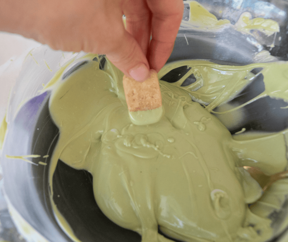 Hand dipping shortbread in melted white chocolate matcha. 
