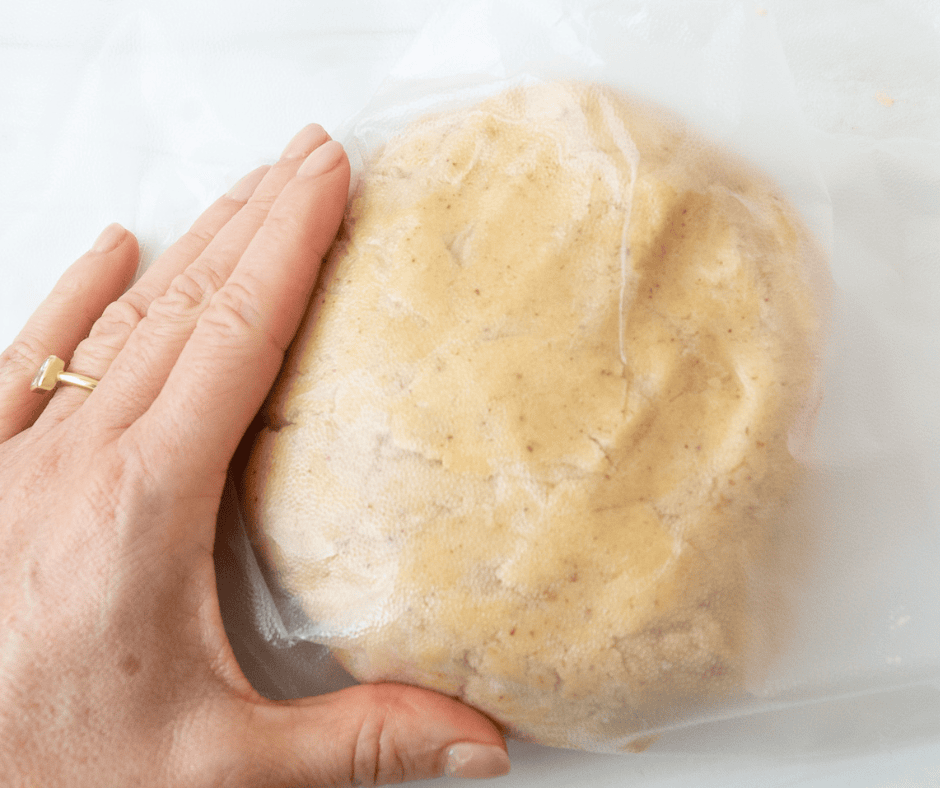 Hand wrapping dough in plastic wrap