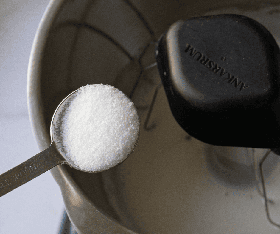 Adding granulated sugar one tablespoon at a time to frothy egg whites in a stand mixer to build a glossy meringue